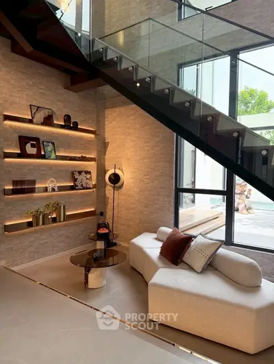 Modern living room with stylish decor and glass staircase, perfect for luxury living.