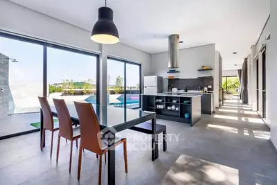 Modern open-plan kitchen and dining area with pool view, sleek design, and natural light.