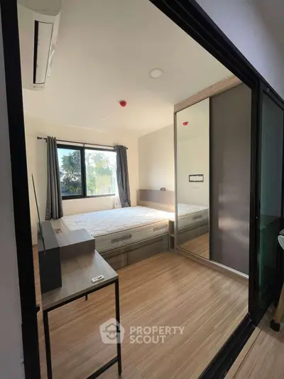 Modern bedroom with mirrored wardrobe and large window for natural light.