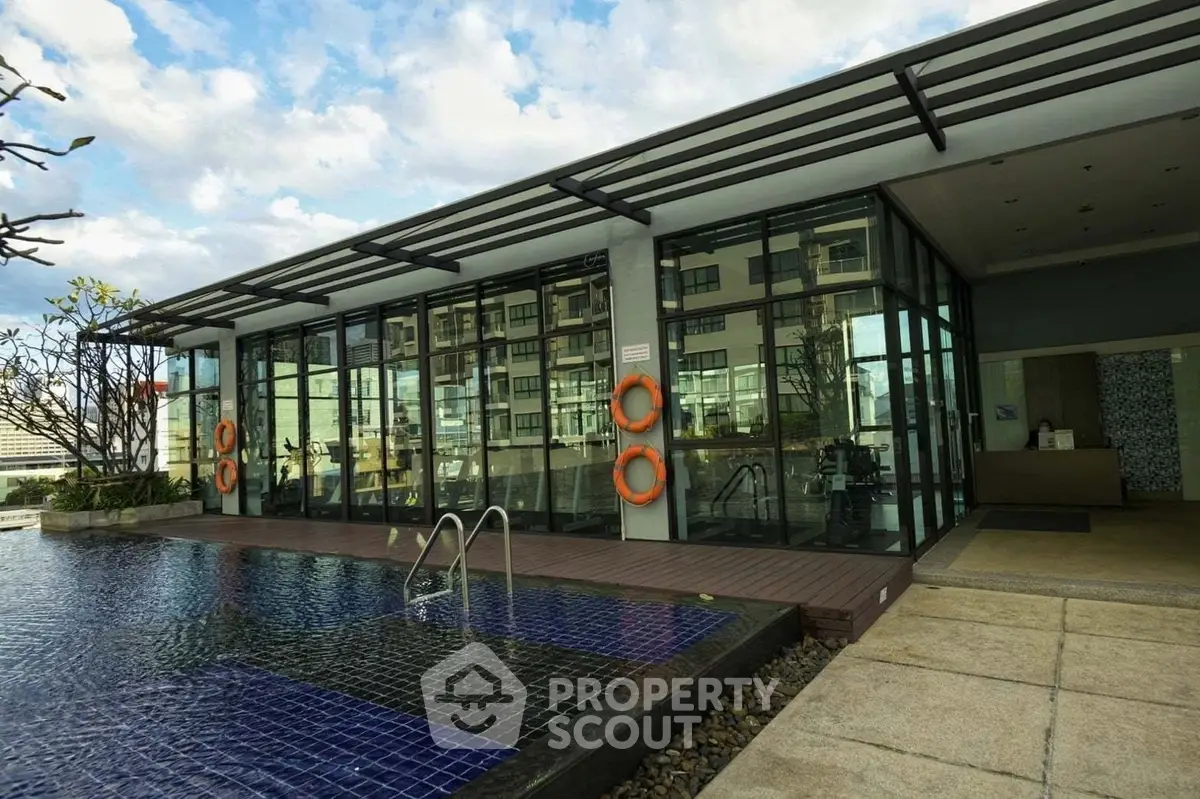 Luxurious modern building with poolside view and glass facade, perfect for upscale living.