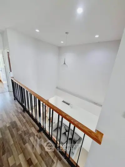 Modern loft-style living area with high ceiling and sleek railing design