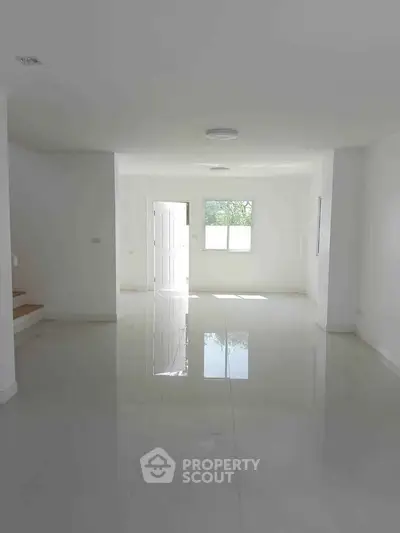 Spacious and bright living room with glossy tiled floors and ample natural light.
