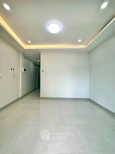 Spacious empty living room with modern lighting and sleek tile flooring
