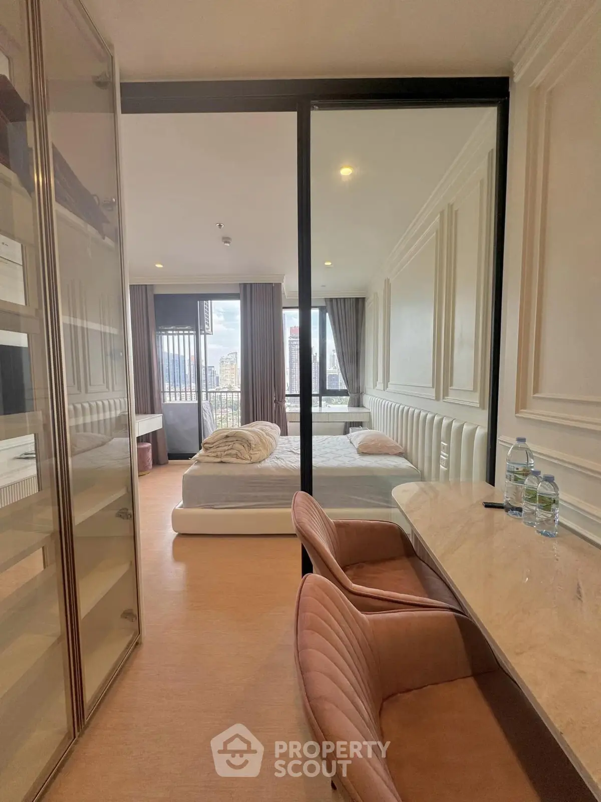 Luxurious bedroom with city view, elegant decor, and modern furnishings in a high-rise apartment.