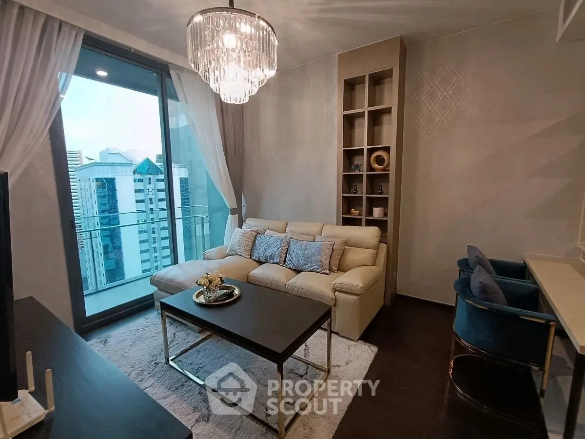 Elegant living room with modern decor and city view balcony, featuring plush seating and chic chandelier.