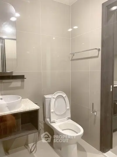 Modern bathroom with sleek fixtures and neutral tiles, featuring a stylish vanity and toilet.