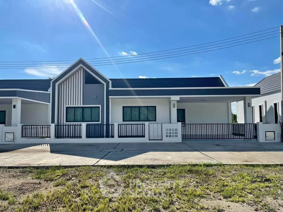 Modern single-story house with sleek design and spacious driveway under a clear blue sky.