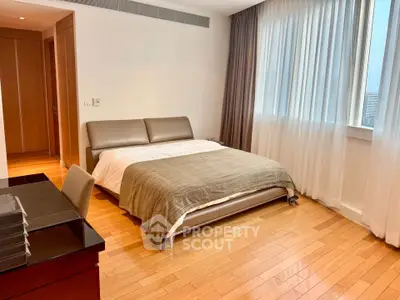Spacious bedroom with modern furnishings and large window offering natural light.