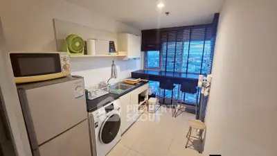Modern kitchen with washing machine and city view, featuring sleek appliances and stylish bar seating.