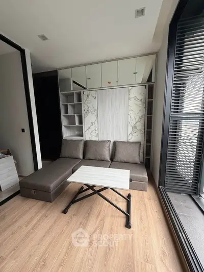 Modern living room with sleek sofa, stylish table, and floor-to-ceiling windows for natural light.