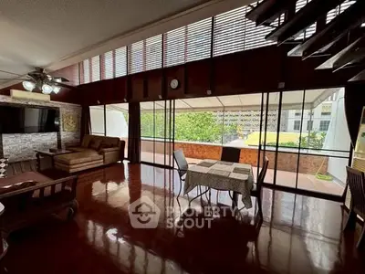 Spacious living room with large windows and polished wooden floors, perfect for entertaining.