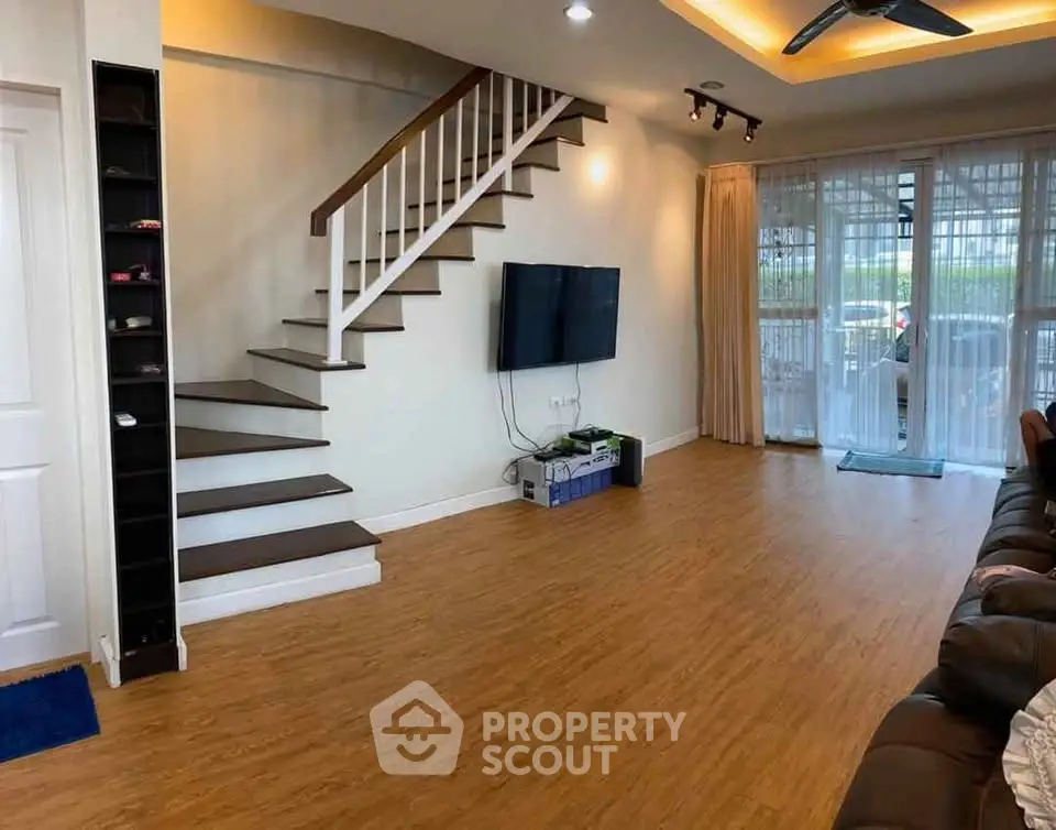 Spacious living room with modern staircase and wall-mounted TV, perfect for family gatherings.