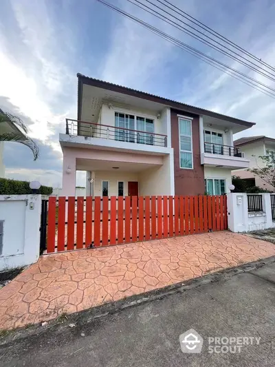 Modern two-story house with red fence and spacious driveway