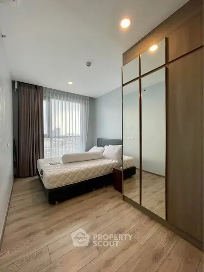 Modern bedroom with large window and mirrored wardrobe in a stylish apartment.