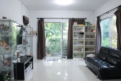 Spacious living room with glass cabinets and garden view, perfect for collectors.