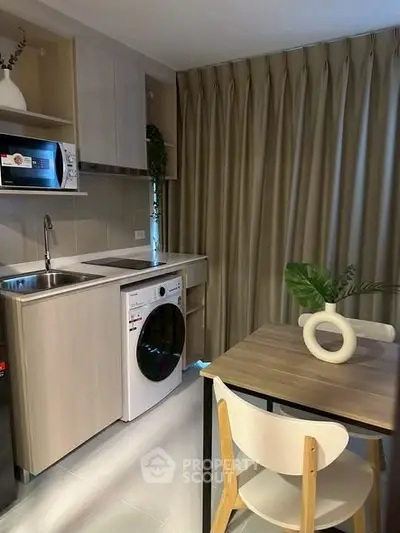 Modern kitchen with washing machine and dining area in compact apartment