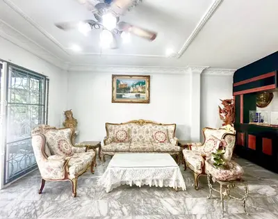 Elegant living room with vintage furniture and marble flooring, featuring a classic painting and ornate decor.