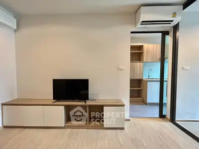 Modern living room with sleek TV stand and view into stylish kitchen