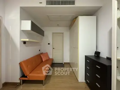 Modern living room with sleek furniture and minimalist design, featuring a stylish orange sofa and ample storage space.