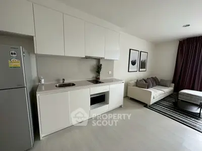 Modern open-layout kitchen and living room with sleek white cabinetry and cozy seating area.