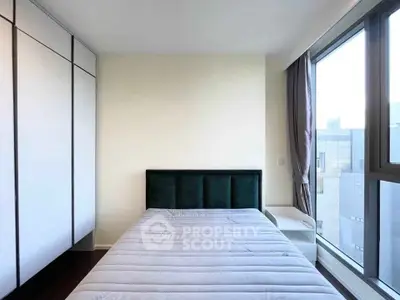 Modern bedroom with large window and built-in wardrobe offering city views.