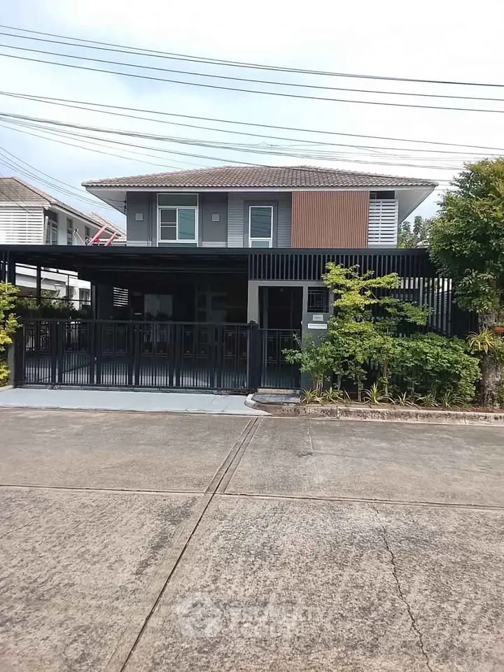 Modern two-story house with sleek design and spacious driveway in a suburban neighborhood.