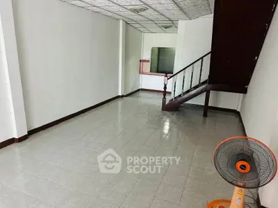 Spacious empty room with tiled floor and staircase, ideal for customization.