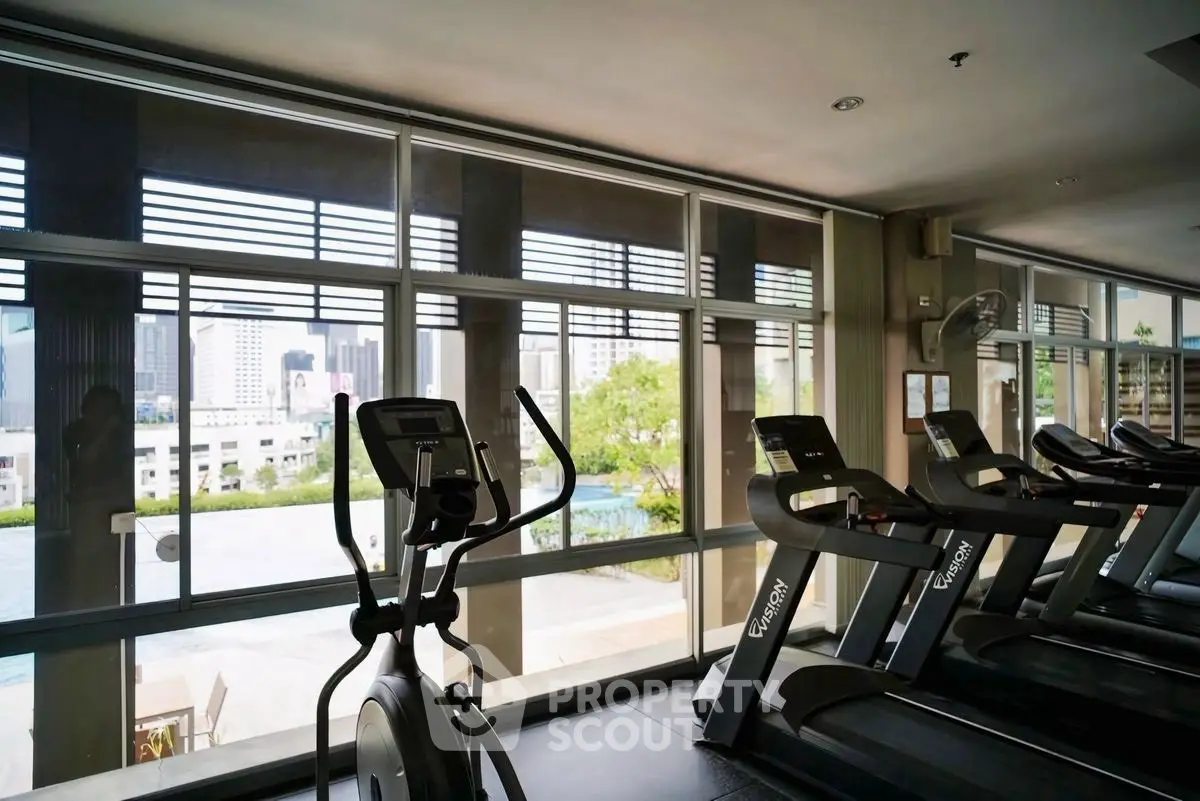 Modern gym with city view and state-of-the-art equipment in luxury building.