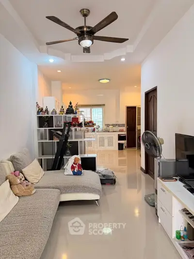 Spacious living room with modern decor and ceiling fan, ideal for family gatherings.