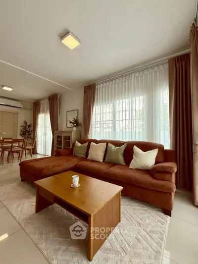 Spacious living room with elegant decor and natural light, featuring a cozy brown sofa and stylish dining area.