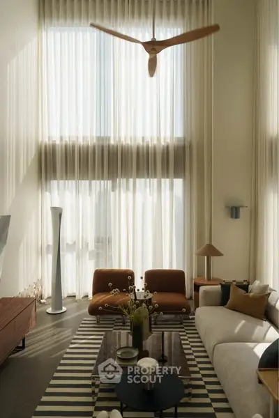 Luxurious living room with high ceilings, elegant decor, and natural light streaming through tall windows.