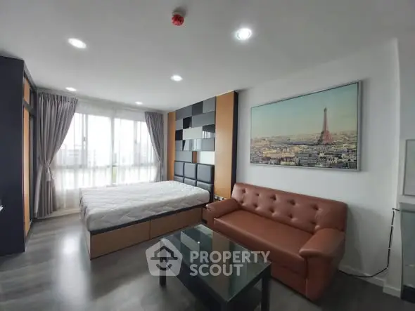 Modern bedroom with stylish decor and large window offering natural light
