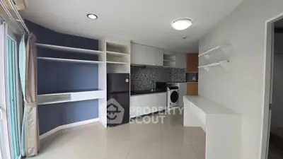 Modern kitchen with sleek cabinetry, washing machine, and refrigerator in a compact open layout.