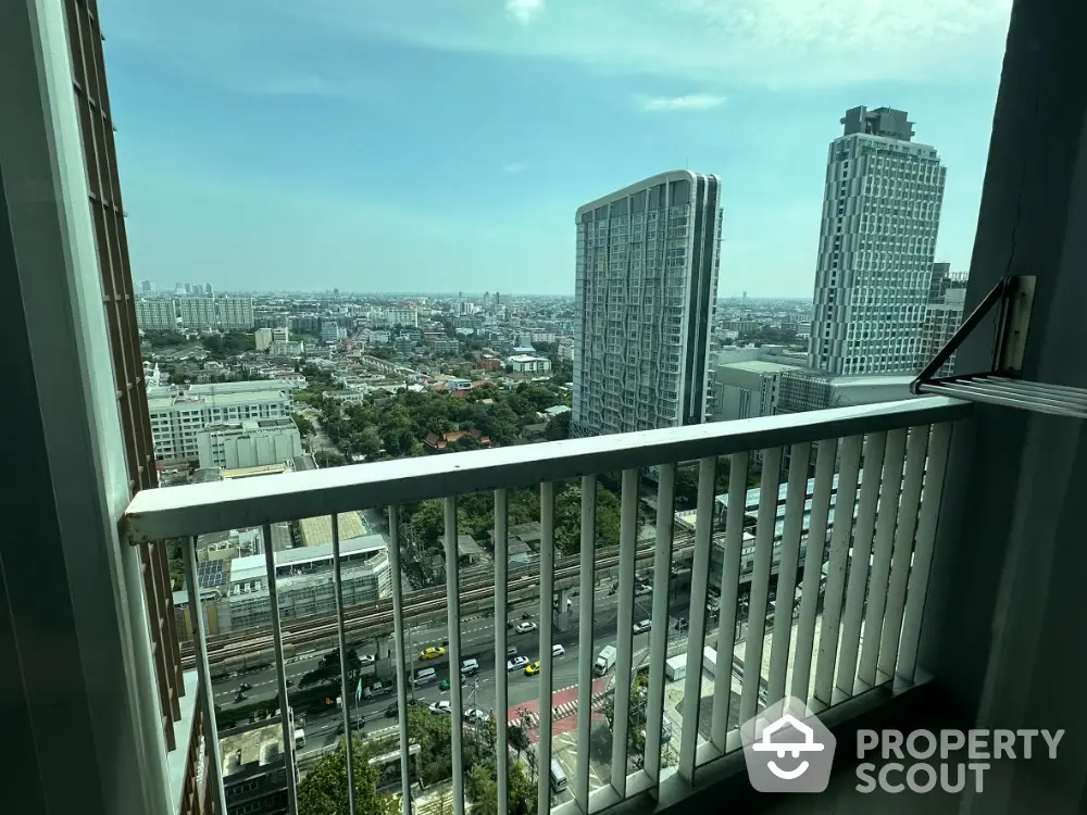 Stunning high-rise balcony view overlooking cityscape with modern skyscrapers and clear blue sky.