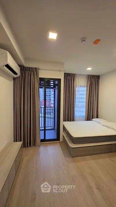 Modern bedroom with balcony access and sleek wooden flooring