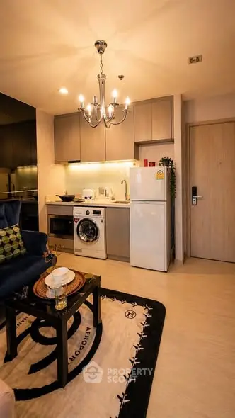Modern kitchen with washing machine, fridge, and elegant lighting in cozy apartment.