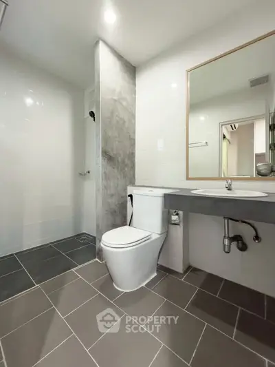 Modern bathroom with sleek design, featuring a toilet, sink, and shower area with stylish tiles.