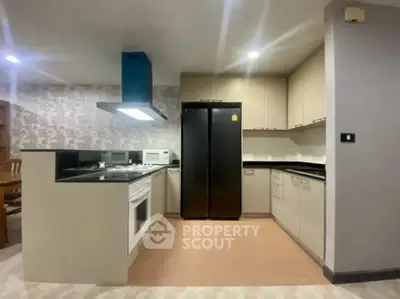 Modern kitchen with sleek cabinetry, built-in oven, and spacious fridge in a stylish apartment.