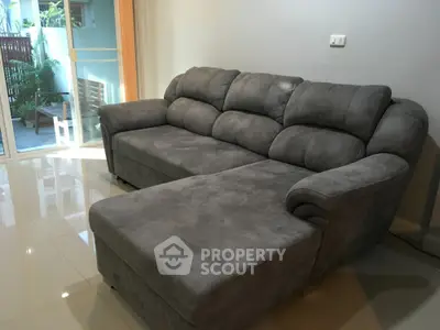 Spacious living room with plush gray sectional sofa and glossy tiled floor, perfect for relaxation.