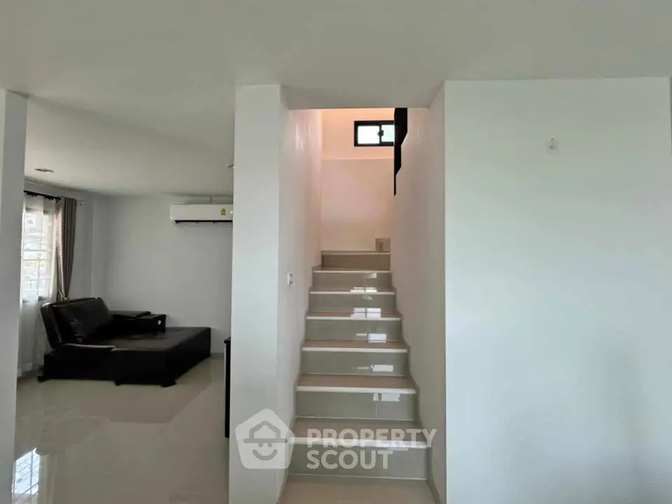 Modern interior with sleek staircase and cozy living area, perfect for stylish urban living.