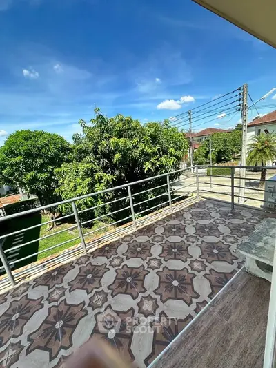 Spacious balcony with intricate tile design and lush green view in a serene neighborhood.