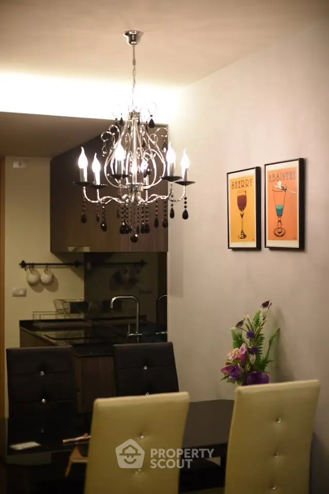 Elegant dining area with chandelier and modern kitchen in background