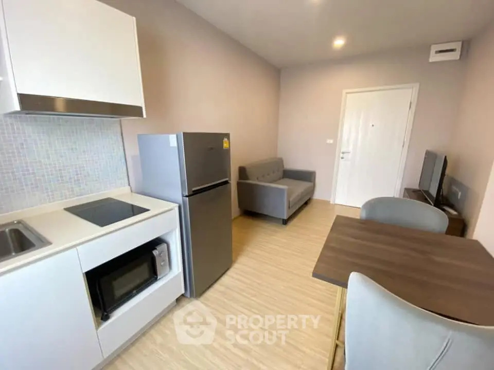 Modern compact living room with kitchenette and dining area in a cozy apartment.