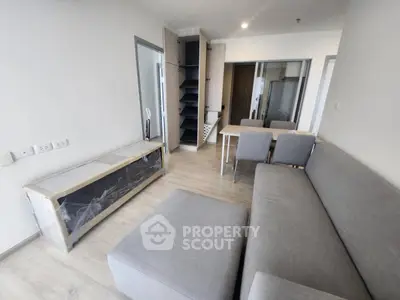 Modern living room with sleek gray sofa, dining area, and built-in storage in a contemporary apartment.