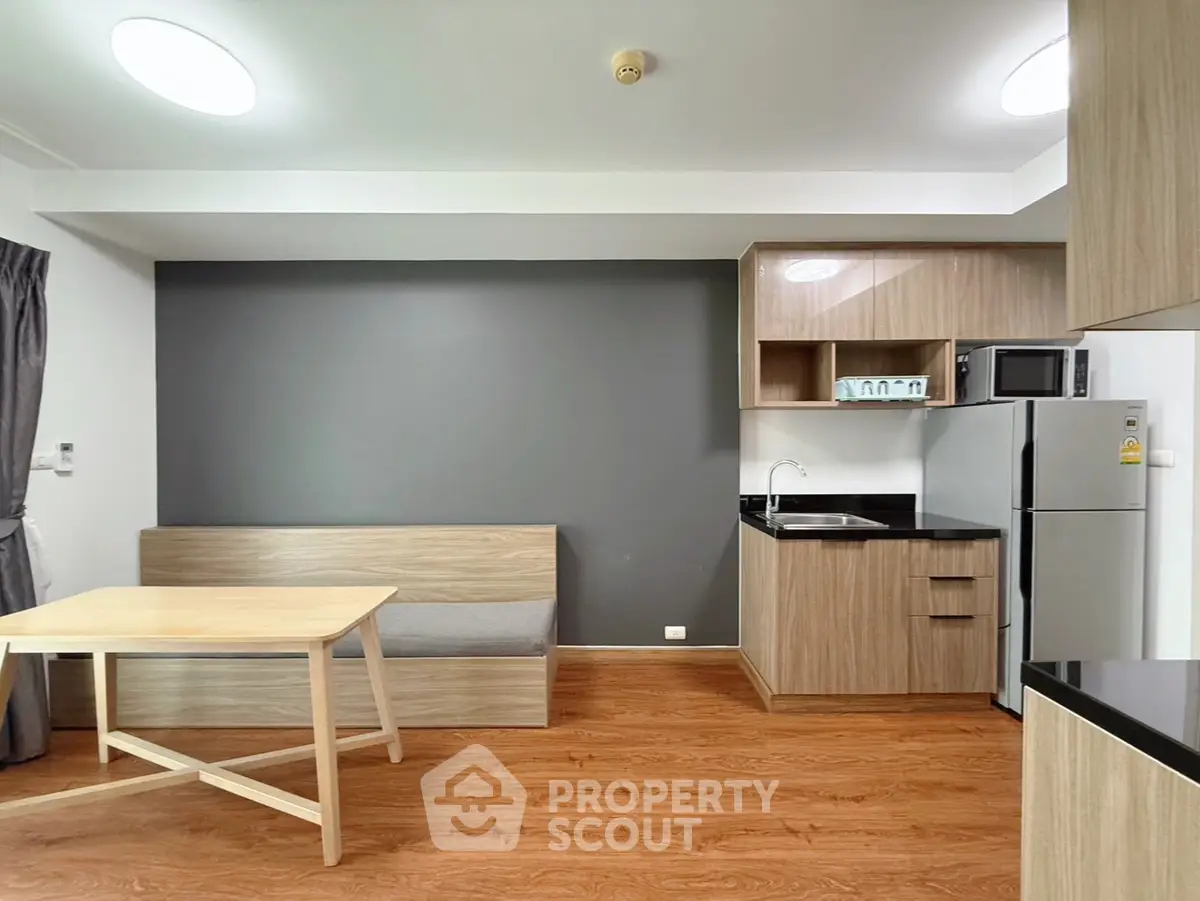 Modern kitchen with sleek cabinetry and cozy dining area in stylish apartment.
