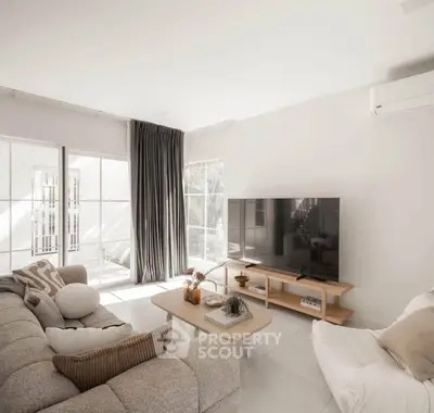 Elegant living room with modern decor, large TV, and natural light from floor-to-ceiling windows.