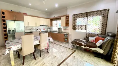 Spacious kitchen with modern appliances and cozy dining area, featuring elegant marble flooring and stylish decor.