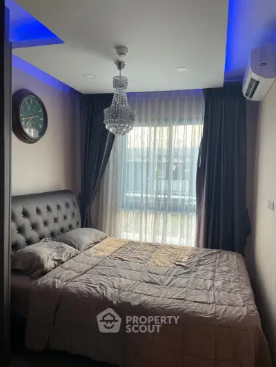 Cozy bedroom with elegant chandelier and modern decor, featuring a plush bed and large window with curtains.