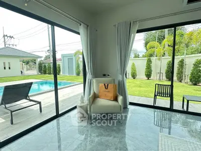 Luxurious living room with pool view and modern decor in a serene setting.