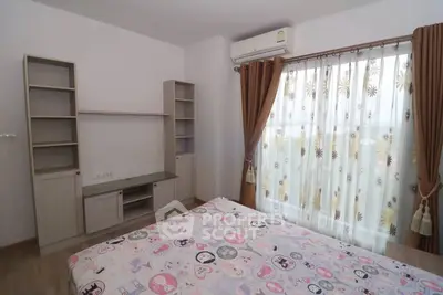 Cozy bedroom with stylish decor and ample natural light from large window.